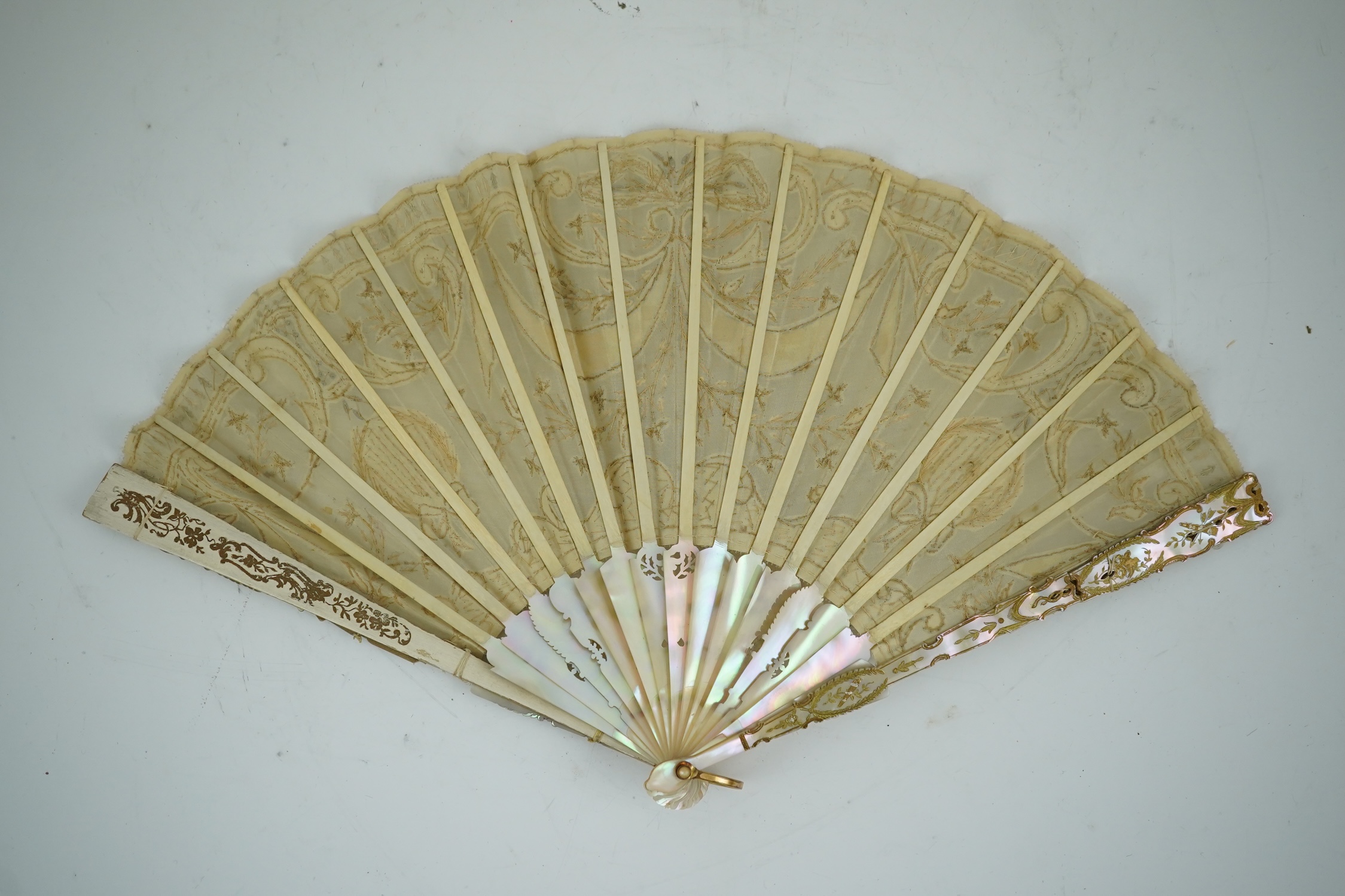 Three French fans: a mother of pearl and sequin fan boxed, a painted silk, feather and bone fan and a gilt decorated bone figural paper fan, the two bone fans having gilt mirrored mounts on the guards, figural paper fan